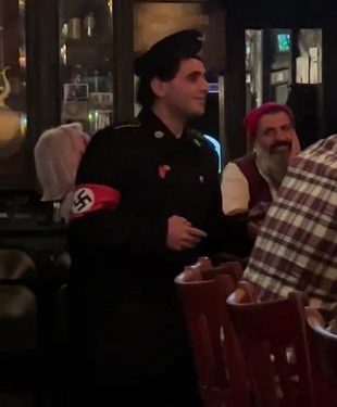 Un homme arrive dans un restaurant de New York, souriant, déguisé en nazi pour Halloween…