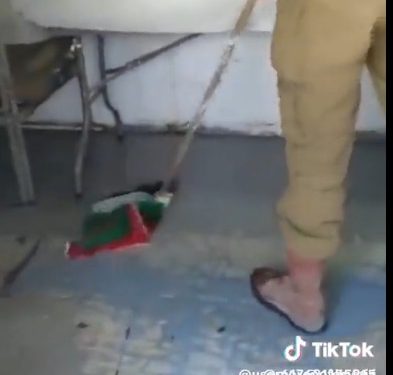 Un soldat de Tsahal passe la serpillière avec un drapeau palestinien